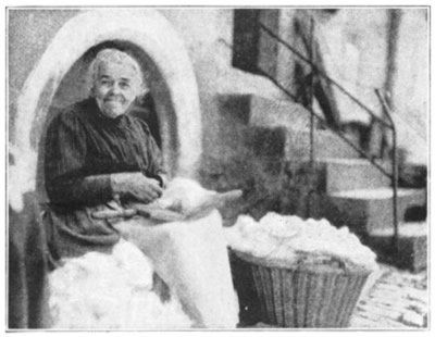 AN OLD WOMAN CLEANING THE COTTON OF A MATTRESS